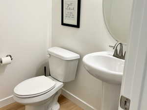 1/2 Bathroom featuring toilet and wood finished floors