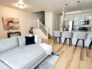 Living area featuring light wood-style flooring, stairs, and a textured ceiling