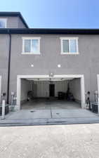 Rear view of property with stucco siding, concrete driveway, and a garage