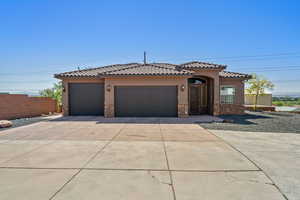 Mediterranean / spanish-style house featuring stone siding, stucco siding, a garage, concrete driveway, and a tile roof