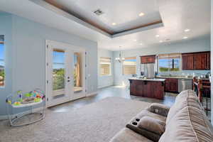 Living room featuring a chandelier, recessed lighting, french doors, and a tray ceiling