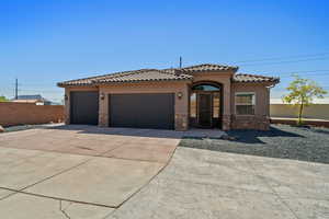 Mediterranean / spanish house featuring stone siding, stucco siding, driveway, an attached garage, and a tiled roof