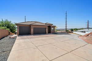 View of front of property with stucco siding, driveway, an attached garage, stone siding, and a tile roof