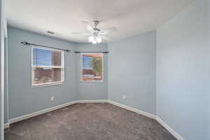Carpeted empty room with ceiling fan and baseboards