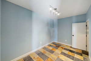 Empty room featuring stone tile flooring and rail lighting