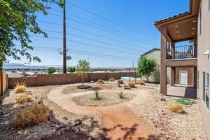 Fenced backyard with a patio area and a balcony