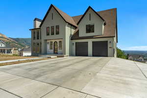 View of front of home with stucco siding, a mountain view, a garage, concrete driveway, and roof with shingles