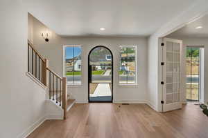 Foyer entrance with wood finished floors, stairs, recessed lighting, and french doors