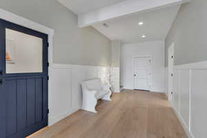 Hallway with a decorative wall, light wood-type flooring, wainscoting, recessed lighting, and a chandelier