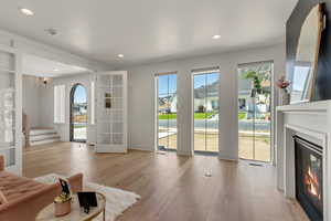 Unfurnished living room with a glass covered fireplace, light wood-style flooring, recessed lighting, and french doors