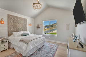Bedroom featuring light wood-type flooring, a chandelier, and lofted ceiling
