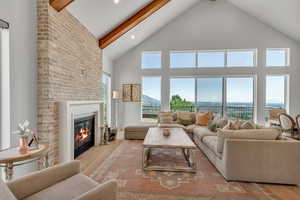 Living area with high vaulted ceiling, a fireplace, wood finished floors, beamed ceiling, and recessed lighting