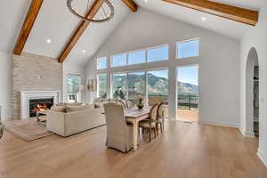 Living room featuring a mountain view, beam ceiling, high vaulted ceiling, wood finished floors, and a large fireplace