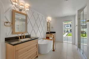 Full bathroom with two vanities, a soaking tub, and a stall shower