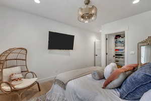 Bedroom with wood finished floors, a spacious closet, recessed lighting, and a closet