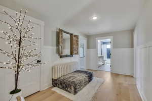 Sitting room featuring a wainscoted wall, light wood-style floors, and a chandelier