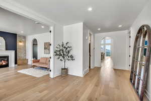 Entryway featuring arched walkways, light wood-type flooring, a glass covered fireplace, and recessed lighting