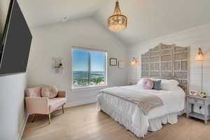 Bedroom featuring a chandelier, lofted ceiling, and light wood-style flooring
