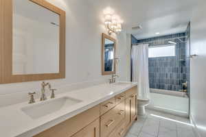 Full bathroom with double vanity, shower / tub combo, and marble look tiles