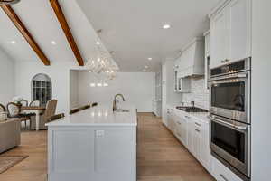 Kitchen with appliances with stainless steel finishes, tasteful backsplash, recessed lighting, white cabinetry, and light wood-style floors