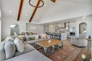 Living room with arched walkways, a chandelier, light wood-style flooring, beam ceiling, and recessed lighting