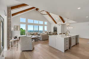 Kitchen featuring beam ceiling, high vaulted ceiling, stainless steel dishwasher, a chandelier, and hanging light fixtures