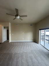Carpeted spare room featuring a ceiling fan and baseboards