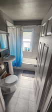 Bathroom featuring a textured ceiling, shower / bath combo, and tile patterned floors