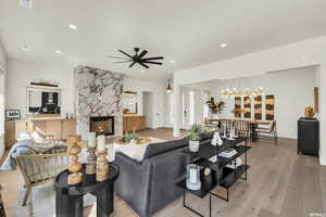 Living area featuring recessed lighting, a premium fireplace, a chandelier, a ceiling fan, and light wood-type flooring