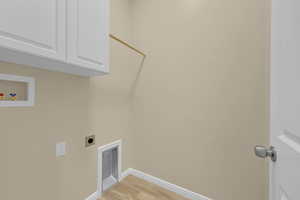 Laundry area with hookup for an electric dryer, light wood-style flooring, cabinet space, and washer hookup