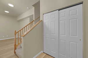 Stairs with wood finished floors and recessed lighting