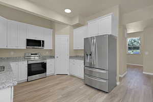 Kitchen featuring stainless steel appliances, white cabinetry, and light wood-style flooring