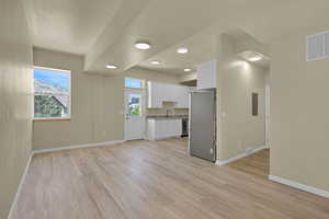 Unfurnished living room featuring light wood-type flooring, recessed lighting, and electric panel