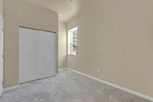 Unfurnished bedroom featuring light carpet and a closet