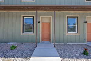 View of exterior entry featuring a porch and board and batten siding