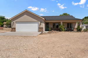 Ranch-style house with concrete driveway, stucco siding, a garage, brick siding, and a porch