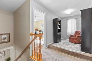 Living area with an upstairs landing, wood finished floors, and a ceiling fan