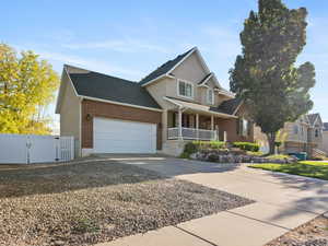 Traditional-style home featuring a gate, driveway, an attached garage, a porch, and brick siding