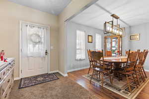 Dining space with dark wood-style floors, dark carpet, and a chandelier