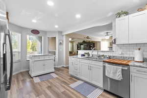 Kitchen featuring stainless steel appliances, a peninsula, recessed lighting, decorative backsplash, and light wood-style flooring