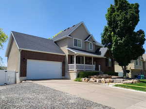 Traditional-style home with a gate, brick siding, concrete driveway, an attached garage, and a residential view