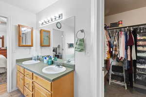 Full bath featuring ensuite bath, double vanity, and a walk in closet