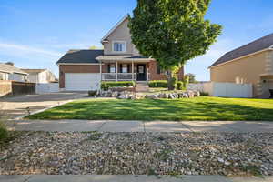 View of front of home with covered porch, brick siding, an attached garage, and driveway