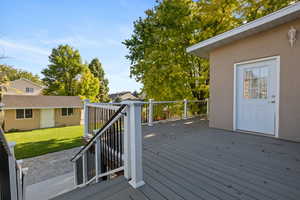 Wooden terrace featuring an outbuilding and a lawn