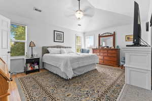 Bedroom featuring light wood finished floors, vaulted ceiling, ceiling fan, and a textured ceiling