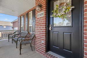 Doorway to property with brick siding and covered porch