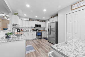 Kitchen with appliances with stainless steel finishes, light stone counters, backsplash, light wood-type flooring, and recessed lighting