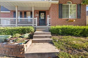 Entrance to property featuring a porch and brick siding