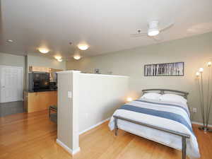 Bedroom featuring black fridge, light wood finished floors, and baseboards