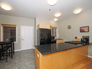 Kitchen with black appliances, a peninsula, a kitchen bar, and baseboards